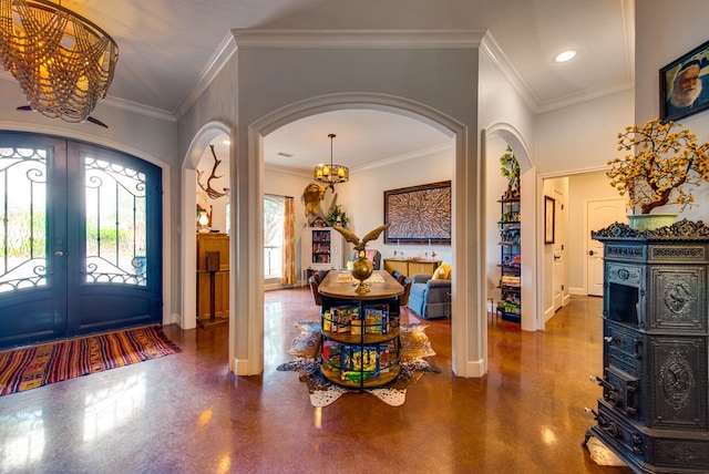 entrance foyer with arched walkways, a chandelier, french doors, baseboards, and ornamental molding