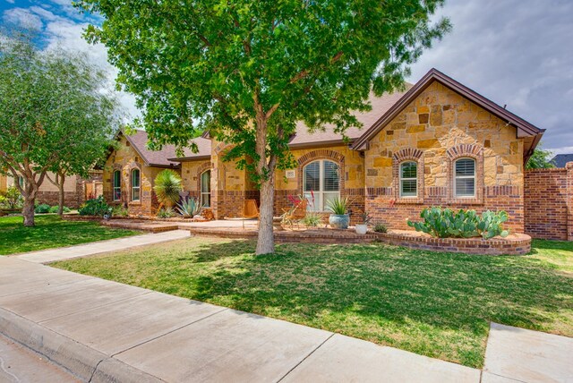1102 Castle Rock Ct, Midland, TX 79705 - english style home featuring stone siding, a front lawn, and brick siding