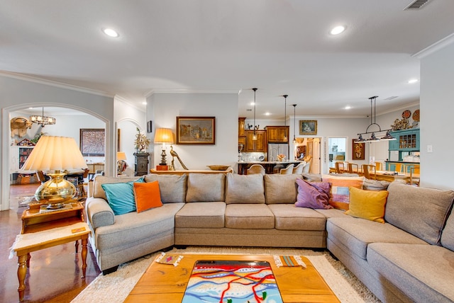 living room featuring crown molding, recessed lighting, arched walkways, and a chandelier