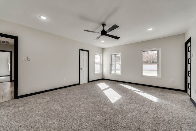 unfurnished room with baseboards, carpet flooring, ceiling fan, and plenty of natural light