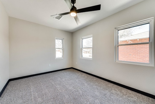 spare room featuring carpet, visible vents, baseboards, and a ceiling fan