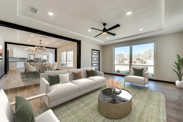 living area with a raised ceiling, light wood finished floors, and recessed lighting