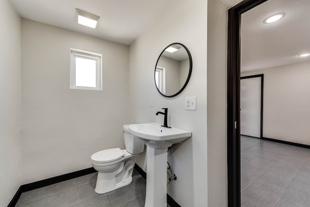 bathroom featuring toilet, baseboards, and recessed lighting