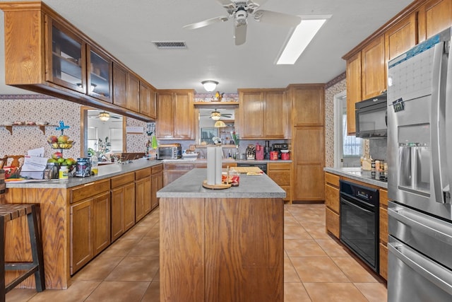 kitchen with light tile patterned flooring, decorative backsplash, a kitchen island, and black appliances