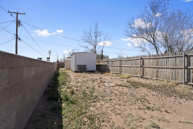 view of yard with a storage unit, an outbuilding, and a fenced backyard