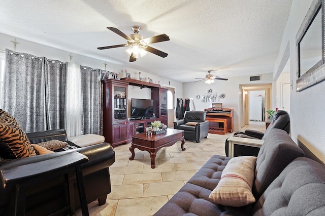 living area featuring visible vents, a textured ceiling, and ceiling fan