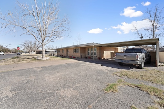 ranch-style house featuring aphalt driveway, a carport, and brick siding