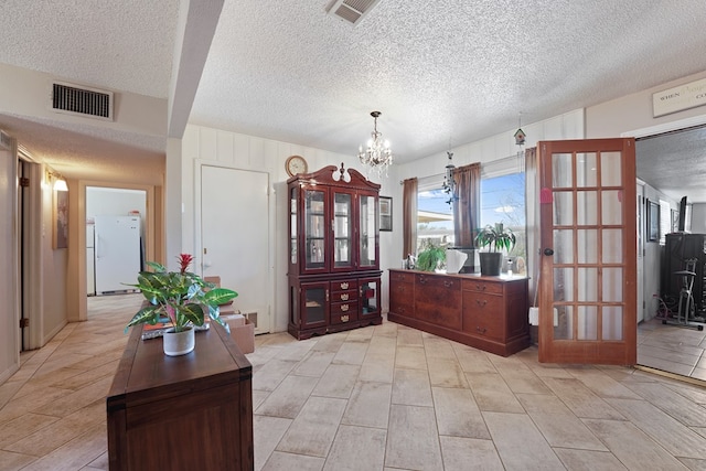 entrance foyer with visible vents, a textured ceiling, and an inviting chandelier