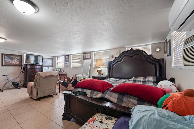 bedroom with a textured ceiling, light tile patterned flooring, and a wall mounted AC