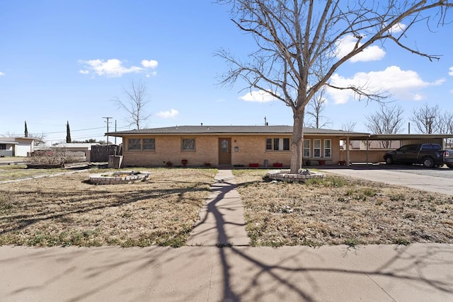 ranch-style house with an attached carport, fence, brick siding, and driveway