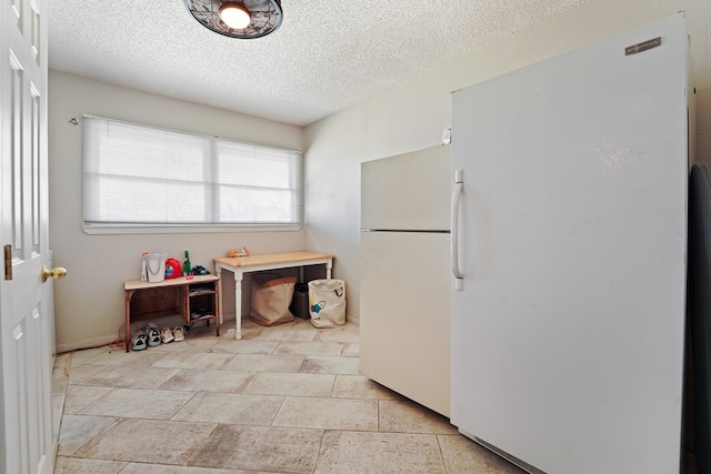 kitchen featuring a textured ceiling and freestanding refrigerator