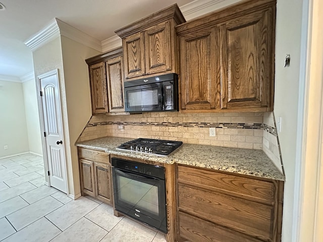 kitchen with light tile patterned floors, light stone counters, backsplash, black appliances, and crown molding