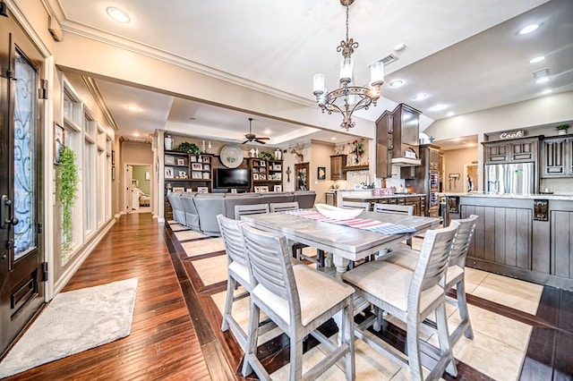 dining space featuring recessed lighting, a raised ceiling, ornamental molding, wood finished floors, and ceiling fan with notable chandelier