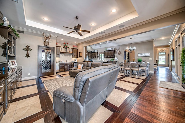 living area with baseboards, ornamental molding, a tray ceiling, light wood-style floors, and recessed lighting