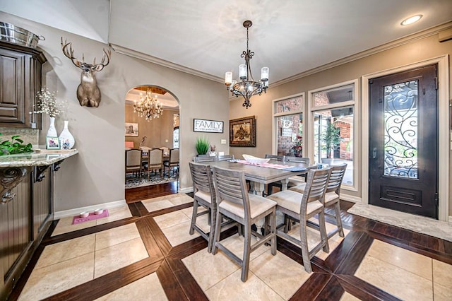 dining space with arched walkways, a notable chandelier, recessed lighting, ornamental molding, and baseboards