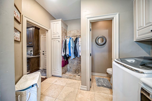 full bathroom featuring toilet, tile patterned flooring, washer / clothes dryer, and a tile shower