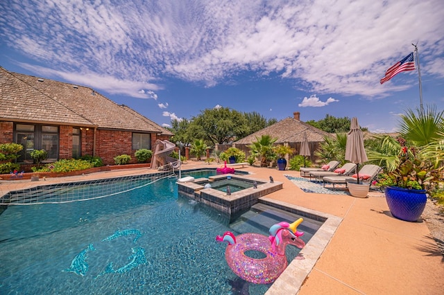 view of swimming pool featuring a patio area, a pool with connected hot tub, and fence