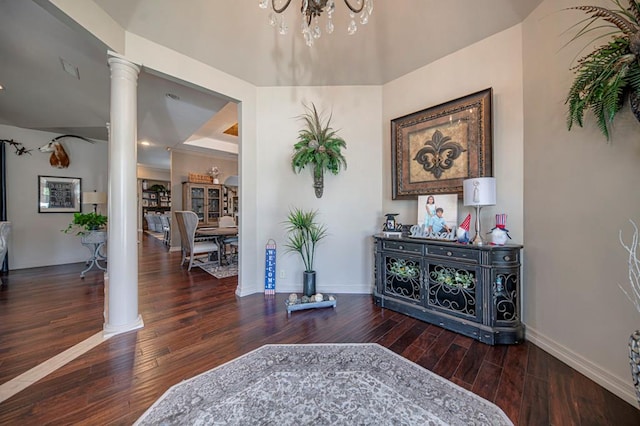 interior space with ornate columns, baseboards, a chandelier, and hardwood / wood-style floors