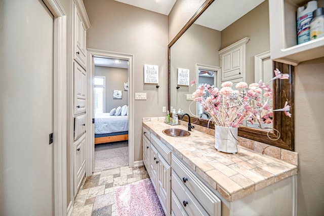 bathroom featuring stone finish flooring, ensuite bath, vanity, and baseboards