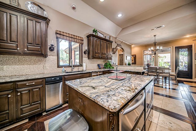 kitchen with tasteful backsplash, a peninsula, light stone countertops, a sink, and recessed lighting