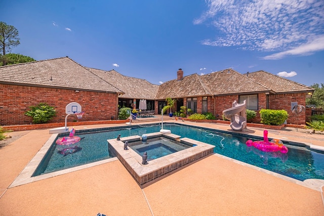 view of swimming pool with a water slide, a patio area, and a pool with connected hot tub