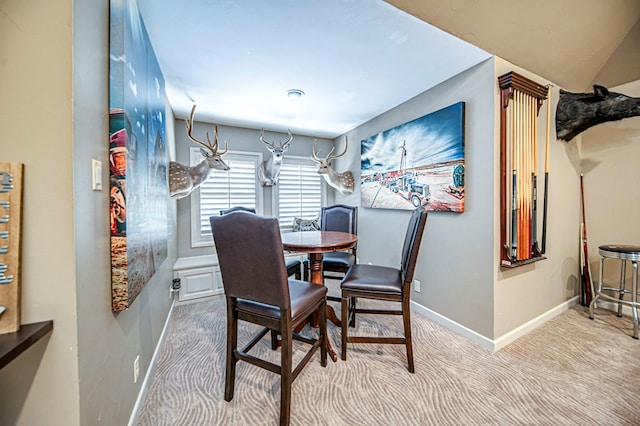 carpeted dining room featuring baseboards