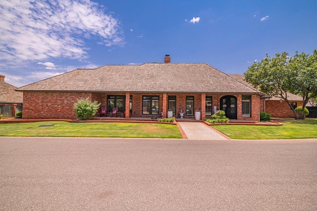 ranch-style house featuring a chimney, a front lawn, and brick siding