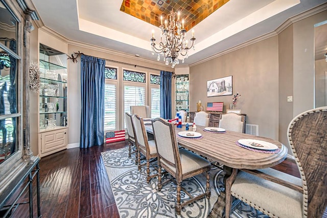 dining room featuring visible vents, wood-type flooring, a tray ceiling, crown molding, and a notable chandelier