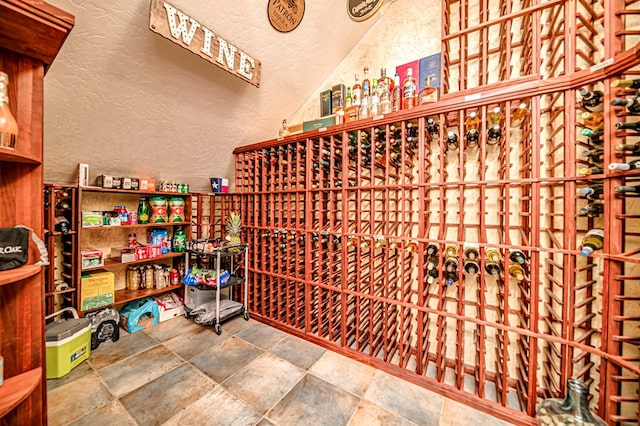 wine cellar with lofted ceiling, a textured wall, and stone tile flooring