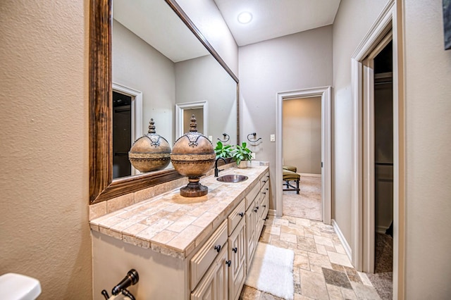 bathroom featuring stone finish flooring, baseboards, and vanity