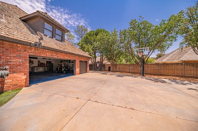 view of side of home with concrete driveway, brick siding, and fence