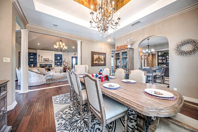 dining space featuring ornate columns, a raised ceiling, and a notable chandelier