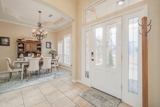 tiled foyer entrance featuring an inviting chandelier, ornamental molding, and a raised ceiling