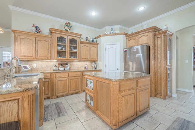 kitchen with crown molding, stainless steel fridge, backsplash, a center island, and light stone countertops