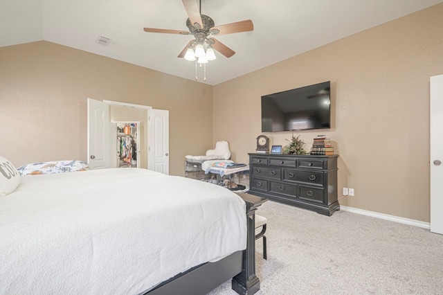 bedroom featuring ceiling fan, a spacious closet, vaulted ceiling, and light carpet