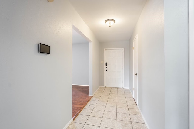 hallway with light tile patterned flooring and baseboards