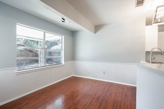 spare room featuring dark wood-type flooring, wainscoting, a sink, and visible vents