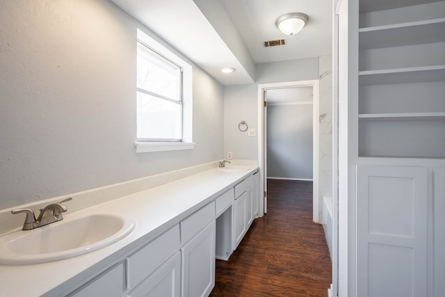 bathroom with double vanity, wood finished floors, a sink, and visible vents