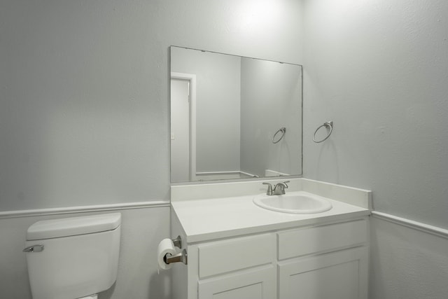 half bathroom featuring vanity and toilet