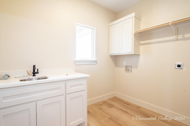 washroom with sink, electric dryer hookup, hookup for a washing machine, cabinets, and light wood-type flooring