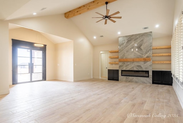 unfurnished living room with high vaulted ceiling, light wood-type flooring, beamed ceiling, ceiling fan, and a tiled fireplace