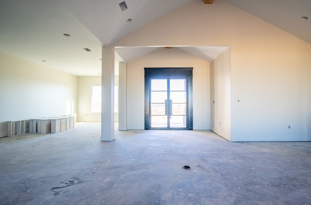 empty room with high vaulted ceiling, concrete flooring, and a healthy amount of sunlight