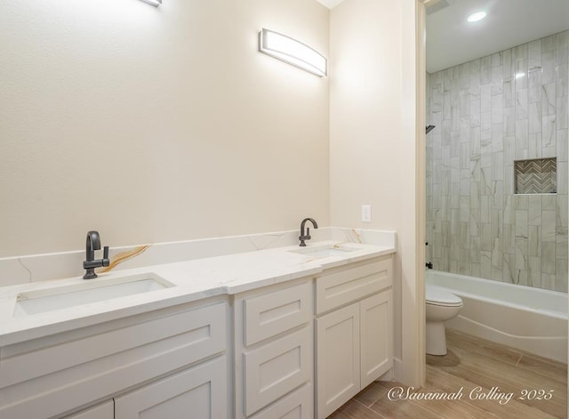 full bathroom featuring vanity, tiled shower / bath, and toilet