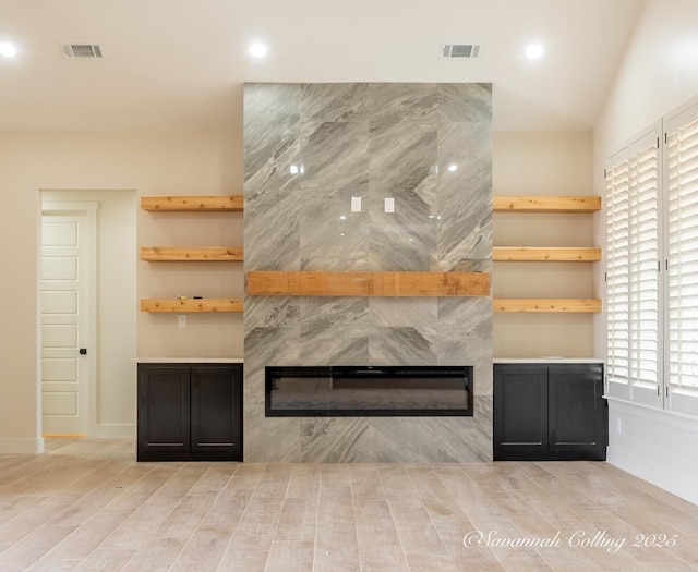 unfurnished living room with a tiled fireplace and light hardwood / wood-style floors