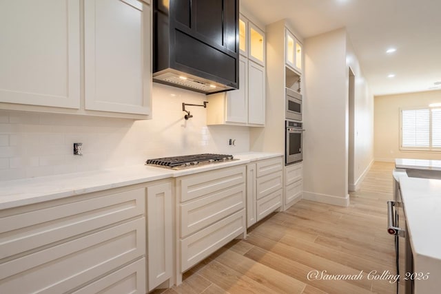 kitchen featuring tasteful backsplash, appliances with stainless steel finishes, white cabinets, and light hardwood / wood-style floors