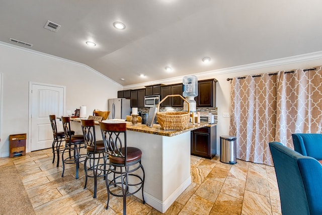 418 Orourke, Midland, TX 79706 - kitchen featuring stainless steel microwave, crown molding, freestanding refrigerator, a breakfast bar area, and lofted ceiling