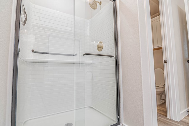 2013 Swenson St, Midland, TX 79705 - bathroom featuring a stall shower, toilet, and wood finished floors