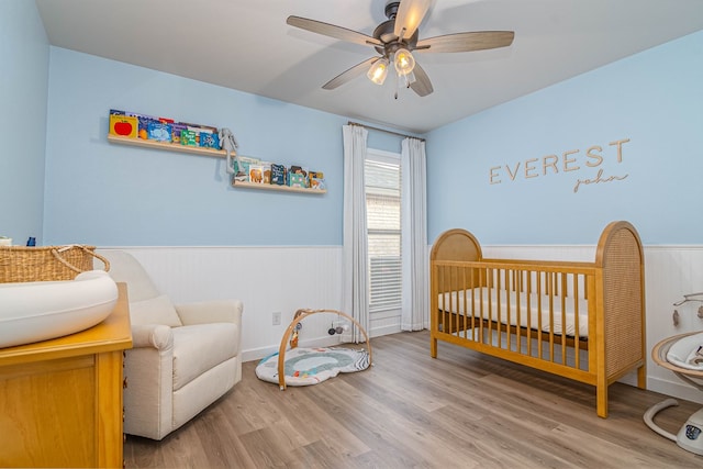 2013 Swenson St, Midland, TX 79705 - bedroom featuring a wainscoted wall, a nursery area, wood finished floors, a sink, and ceiling fan