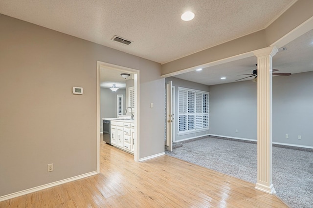 unfurnished room with a textured ceiling, light wood-type flooring, ceiling fan, and sink