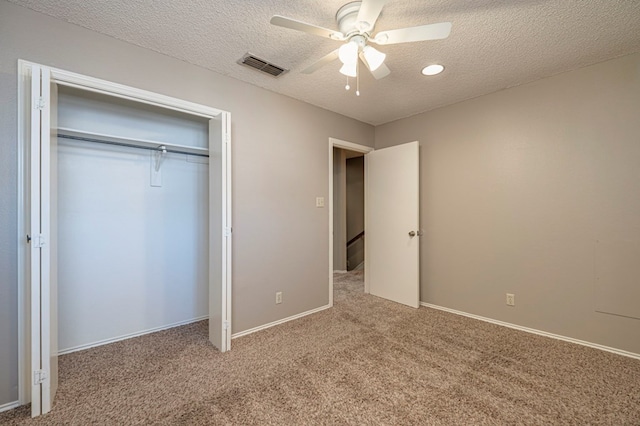 unfurnished bedroom with ceiling fan, a closet, light colored carpet, and a textured ceiling